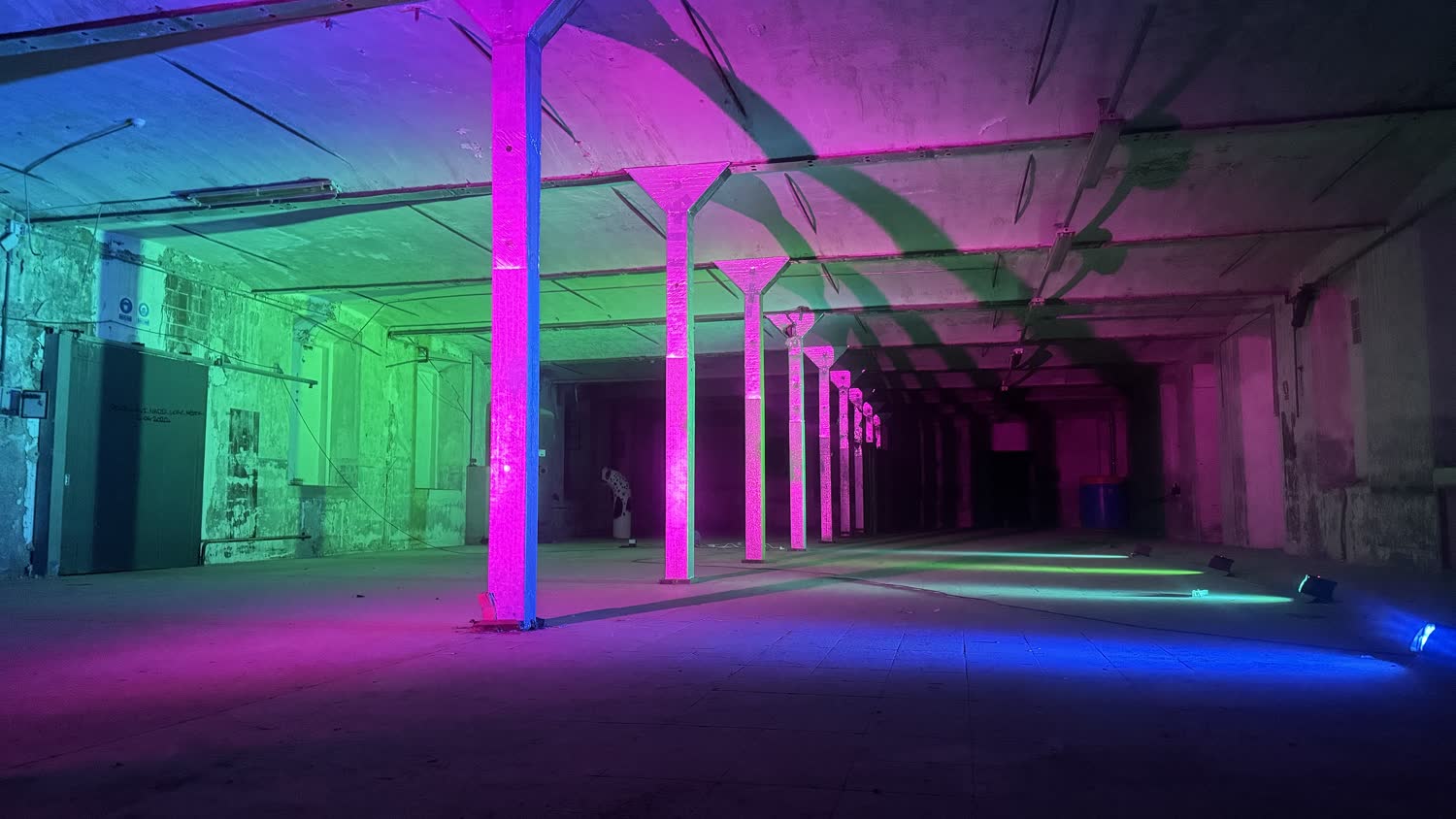 A long colonnaded hall lit in magenta, green and blue at night