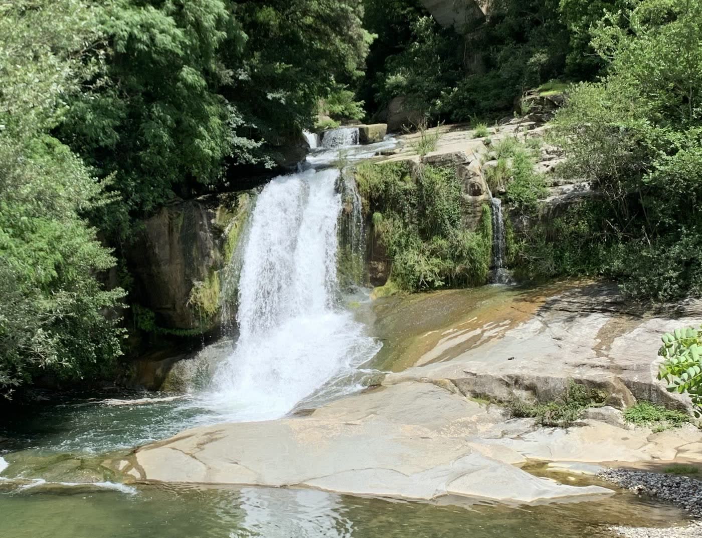 Un salt d&rsquo;aigua que cau en un gorg verd sobre roca clara